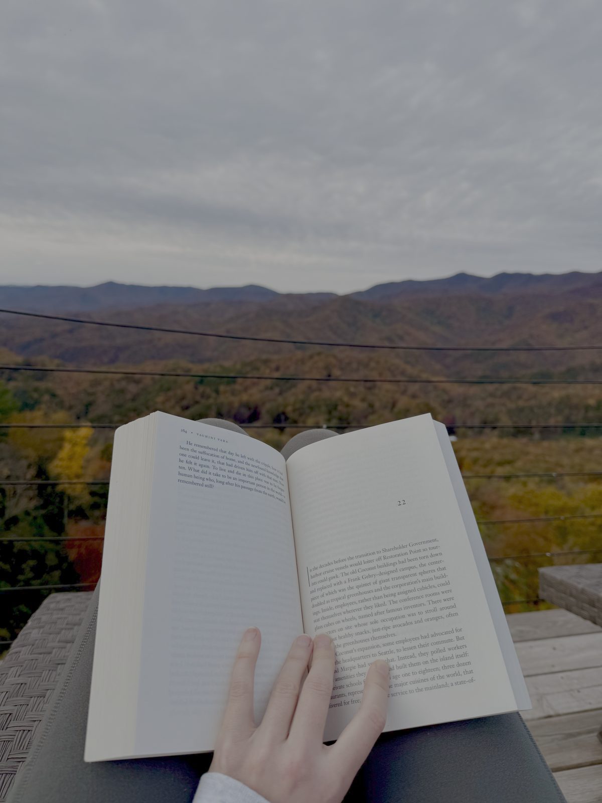 Reading a book on a deck overlooking autumn mountains